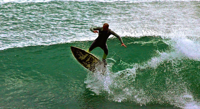 Surfista realizando la maniobra Kick Flip